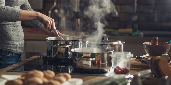 Woman preparing a meal in three pots

