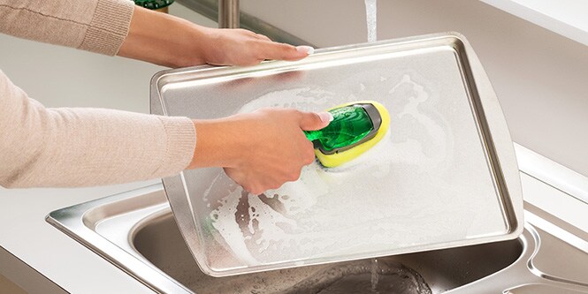 Washing baking tray with Scotch-Brite™ Heavy Duty Dishwand
