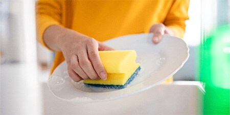 Woman cleaning the dishes with Scotch-Brite® Delicate Nail Saver Scrub Sponge
