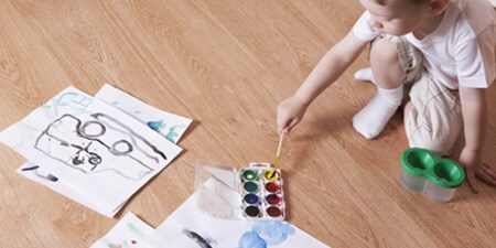 Kid sitting on a clean laminate floor and painting
