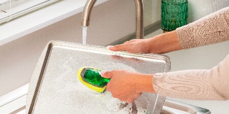 Woman cleaning the baking tray with Scotch-Brite™ Dishwand Classic
